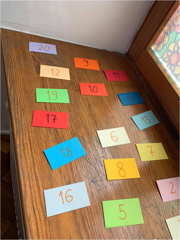 blat stołu, na stole wielokolorowe kartki z zapisanymi na nich liczbami